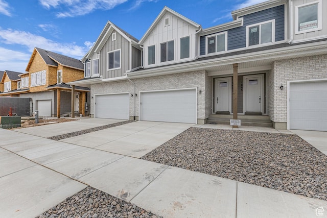 1695 W 2770 S Unit 203, Syracuse, UT 84075 - view of front of property with board and batten siding, a garage, concrete driveway, brick siding, and a residential view