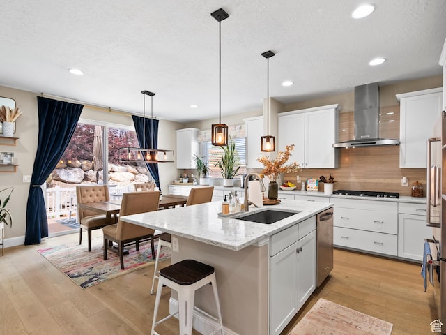 6412 W Chan Reese Dr, West Jordan, UT 84081 - kitchen with wall chimney exhaust hood, light wood-style floors, a textured ceiling, gas stovetop, and an island with sink
