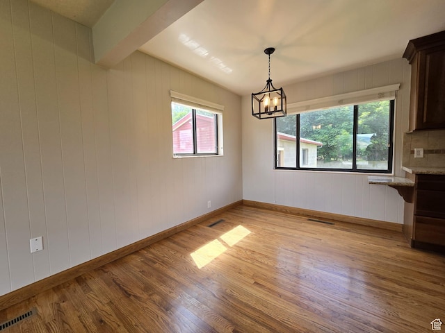 638 E 1050 N, Bountiful, UT 84010 - unfurnished dining area featuring light wood-style floors, a chandelier, and wooden walls