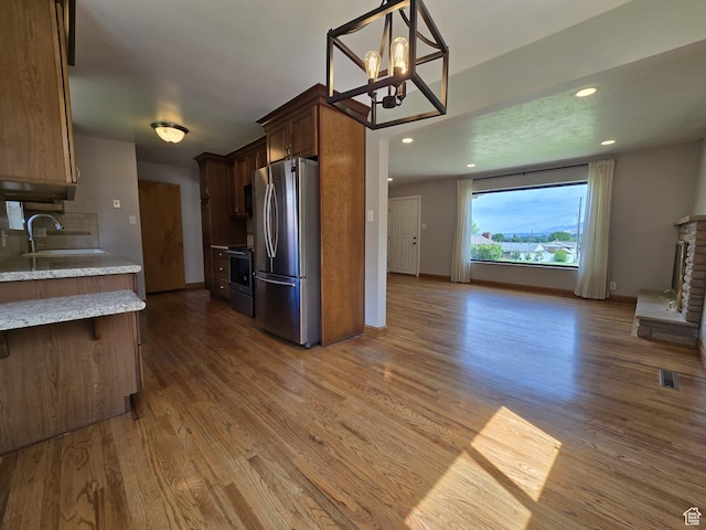 638 E 1050 N, Bountiful, UT 84010 - kitchen with appliances with stainless steel finishes, wood finished floors, a chandelier, open floor plan, and light stone counters