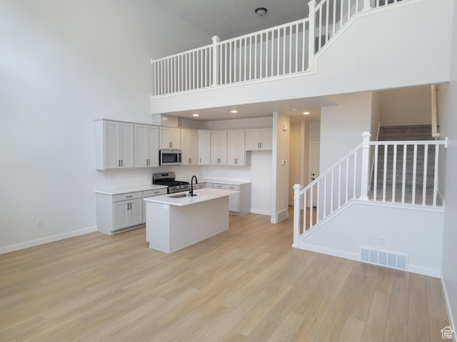 6846 S Static Peak Dr Unit 262, West Jordan, UT 84081 - kitchen featuring stainless steel appliances, a towering ceiling, light countertops, light wood-style floors, and an island with sink
