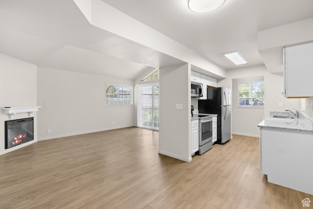 650 S Main St Unit 7105, Bountiful, UT 84010 - kitchen with appliances with stainless steel finishes, light wood-style floors, white cabinetry, a glass covered fireplace, and open floor plan
