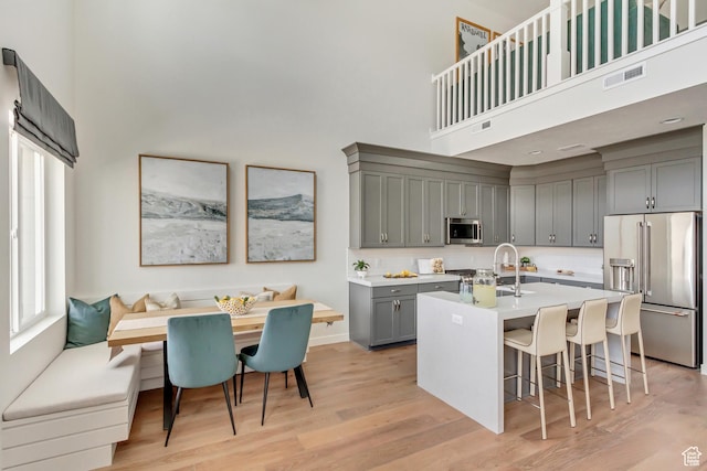 773 W 540 S Unit 344, American Fork, UT 84003 - kitchen featuring appliances with stainless steel finishes, a towering ceiling, breakfast area, gray cabinets, and light wood-style flooring