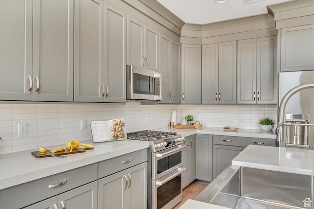 773 W 540 S Unit 344, American Fork, UT 84003 - kitchen featuring appliances with stainless steel finishes, gray cabinets, light countertops, tasteful backsplash, and light wood finished floors