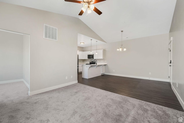 13073 S Newbridge Ln Unit E301, Herriman, UT 84096 - unfurnished living room with ceiling fan, a chandelier, dark carpet, dark wood finished floors, and high vaulted ceiling