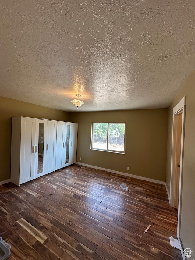 3836 W Jacquelyn St S, West Jordan, UT 84088 - unfurnished bedroom featuring a textured ceiling, dark wood-style floors, and a chandelier