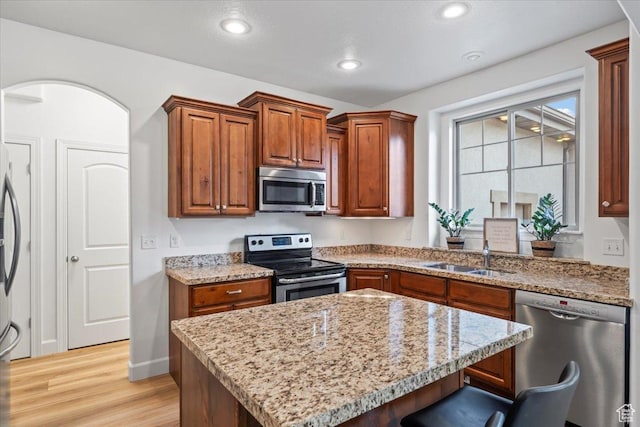 10787 N Town Center Pkwy, Highland, UT 84003 - kitchen featuring stainless steel appliances, light wood-style flooring, a breakfast bar area, light stone counters, and a kitchen island