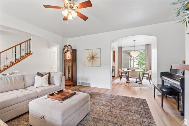 10787 N Town Center Pkwy, Highland, UT 84003 - living area with arched walkways, light wood-style flooring, a ceiling fan, and stairs