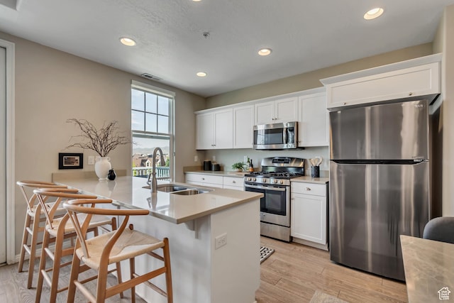 11184 S Waltana Way Unit 205, South Jordan, UT 84095 - kitchen with appliances with stainless steel finishes, recessed lighting, a breakfast bar area, white cabinets, and light wood-type flooring