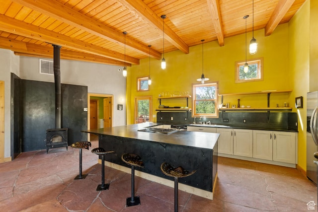 338 Taylor Ln, Castle Valley, UT 84532 - kitchen with a wood ceiling with exposed beams, dark countertops, a high ceiling, open shelves, and a wood stove