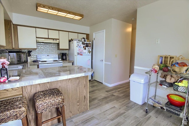 1714 E 5825 S, South Ogden, UT 84403 - kitchen with white appliances, under cabinet range hood, a peninsula, tasteful backsplash, and light countertops