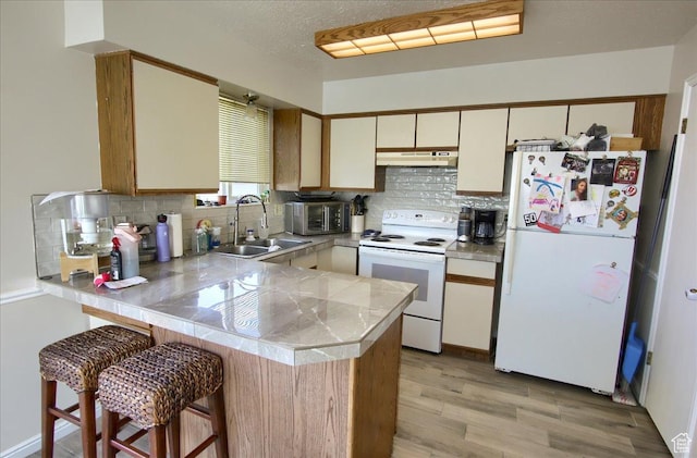 1714 E 5825 S, South Ogden, UT 84403 - kitchen with white appliances, under cabinet range hood, a peninsula, light wood-style flooring, and decorative backsplash