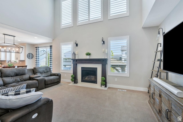 6462 W Shawnee Marie Way, Herriman, UT 84096 - living area featuring light carpet, a brick fireplace, a towering ceiling, and a chandelier