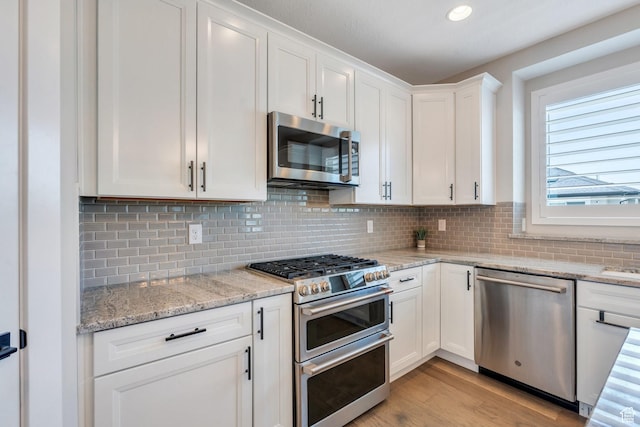 6462 W Shawnee Marie Way, Herriman, UT 84096 - kitchen with appliances with stainless steel finishes, white cabinetry, light wood-type flooring, backsplash, and recessed lighting