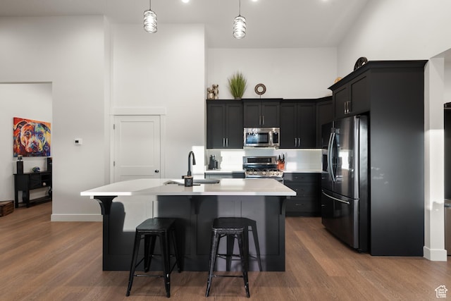 5057 N Foxtail W, Eagle Mountain, UT 84005 - kitchen featuring appliances with stainless steel finishes, a kitchen breakfast bar, light countertops, wood finished floors, and an island with sink
