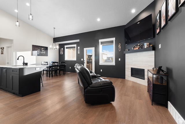5057 N Foxtail W, Eagle Mountain, UT 84005 - living area with a tile fireplace, light wood-style floors, lofted ceiling, recessed lighting, and a chandelier