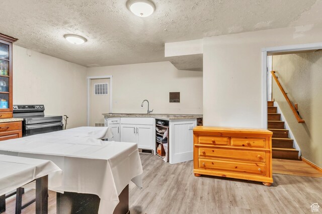 1876 E Casino Way S, Murray, UT 84121 - kitchen with electric range, light wood-style flooring, a textured ceiling, glass insert cabinets, and white cabinetry