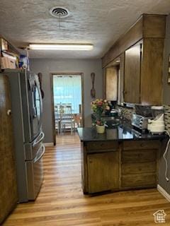 3035 Brinker Ave, Ogden, UT 84403 - kitchen with freestanding refrigerator, light wood-style flooring, dark countertops, and a peninsula