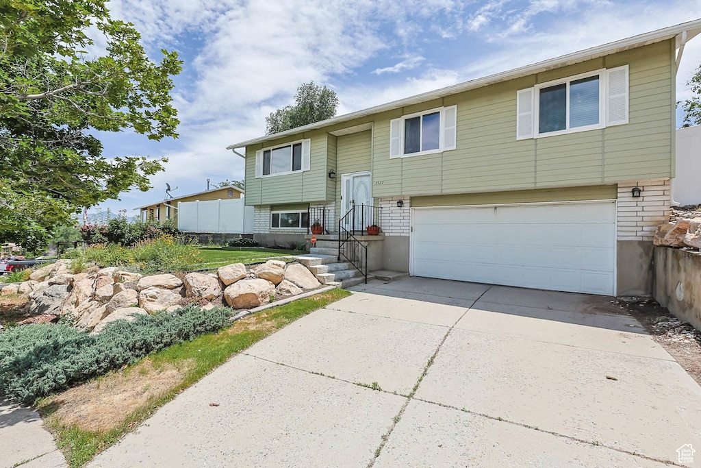 5327 W Mountain Men Dr S, Salt Lake City, UT 84118 - bi-level home with an attached garage, concrete driveway, and brick siding