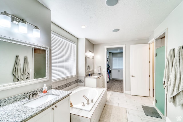 3410 W 2490 S, Hurricane, UT 84737 - bathroom featuring two vanities, a garden tub, a textured ceiling, recessed lighting, and a spacious closet