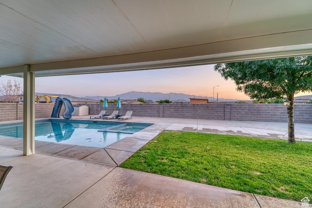 3410 W 2490 S, Hurricane, UT 84737 - pool at dusk featuring a water slide, a patio, a fenced backyard, and a pool with connected hot tub