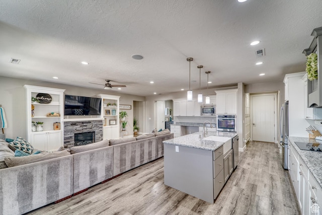 3410 W 2490 S, Hurricane, UT 84737 - kitchen with appliances with stainless steel finishes, open floor plan, light wood finished floors, a textured ceiling, and a fireplace