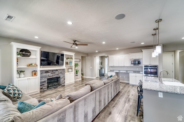 3410 W 2490 S, Hurricane, UT 84737 - living room featuring recessed lighting, light wood-style flooring, a ceiling fan, a textured ceiling, and a fireplace