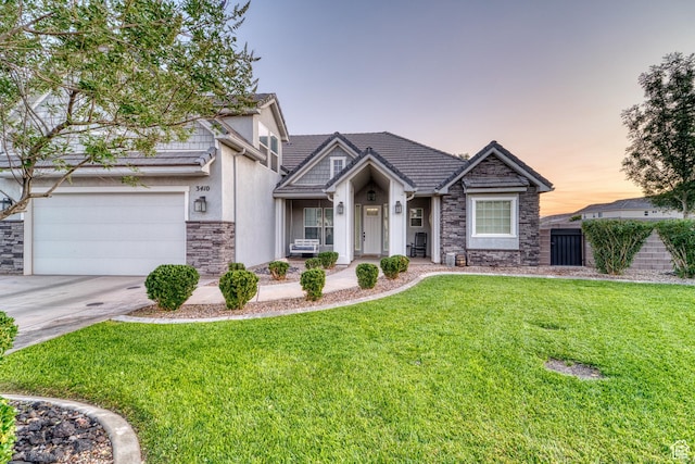 3410 W 2490 S, Hurricane, UT 84737 - view of front of property with stone siding, a lawn, driveway, an attached garage, and stucco siding