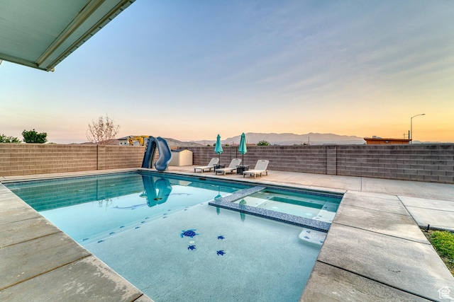 3410 W 2490 S, Hurricane, UT 84737 - pool at dusk featuring a water slide, a patio area, a fenced backyard, and a pool with connected hot tub