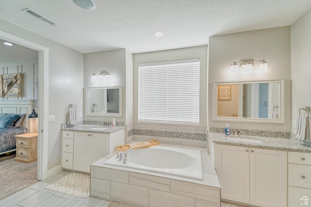 3410 W 2490 S, Hurricane, UT 84737 - ensuite bathroom featuring a bath, two vanities, a textured ceiling, and recessed lighting