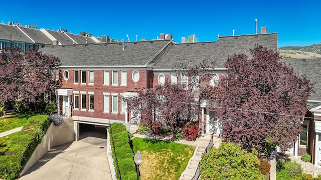 468 N E St, Salt Lake City, UT 84103 - view of property featuring a shingled roof, brick siding, a garage, and concrete driveway