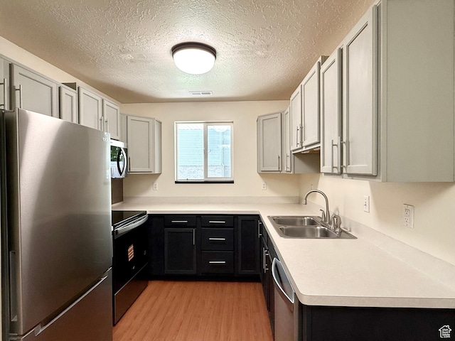 2421 N 400 E Unit E7, North Ogden, UT 84414 - kitchen featuring appliances with stainless steel finishes, light wood-type flooring, a textured ceiling, and light countertops