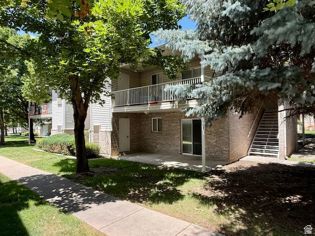 2421 N 400 E Unit E7, North Ogden, UT 84414 - rear view of property with a balcony, a patio, brick siding, and a lawn