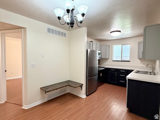2421 N 400 E Unit E7, North Ogden, UT 84414 - kitchen featuring stainless steel appliances, light wood-style flooring, a textured ceiling, light countertops, and a chandelier
