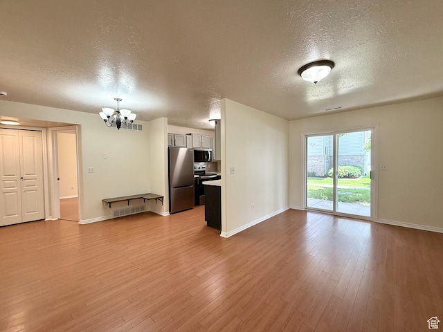 2421 N 400 E Unit E7, North Ogden, UT 84414 - unfurnished living room with a textured ceiling, a chandelier, and wood finished floors