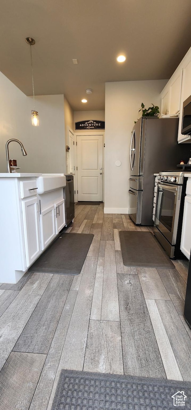 5332 W Scout Plane Ln, South Jordan, UT 84009 - kitchen with stainless steel appliances, white cabinets, light wood-style floors, pendant lighting, and recessed lighting