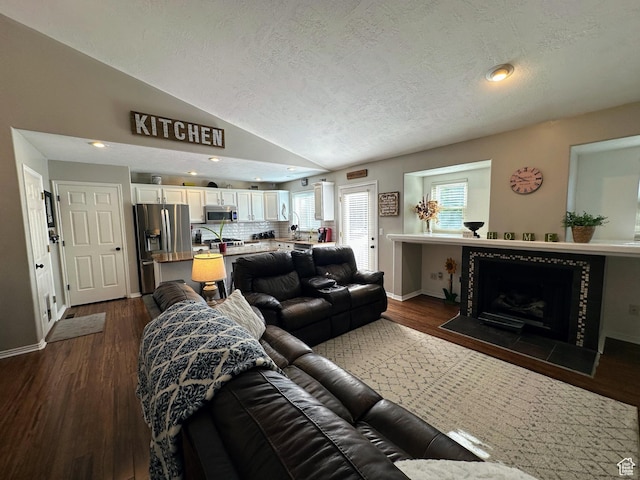 8675 S Pebblecreek Rd, West Jordan, UT 84081 - living area with a textured ceiling, vaulted ceiling, dark wood-style flooring, a tile fireplace, and recessed lighting