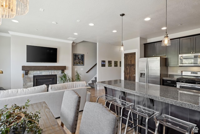 1348 Fiddich Glen Ln, Park City, UT 84098 - kitchen with stainless steel appliances, recessed lighting, a breakfast bar, ornamental molding, and a stone fireplace