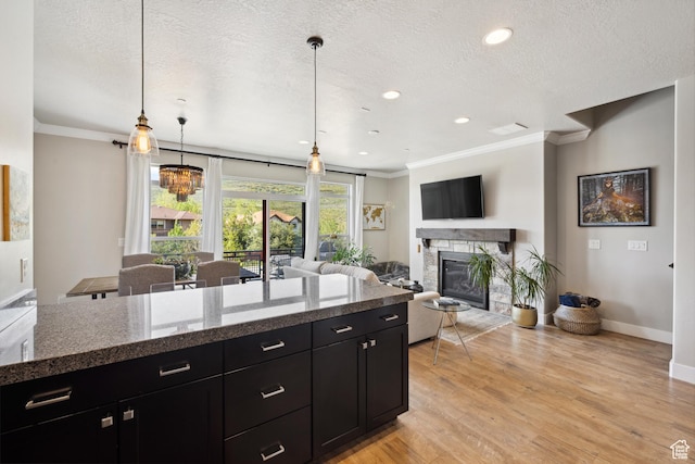 1348 Fiddich Glen Ln, Park City, UT 84098 - kitchen with dark cabinetry, crown molding, a fireplace, light wood finished floors, and a textured ceiling