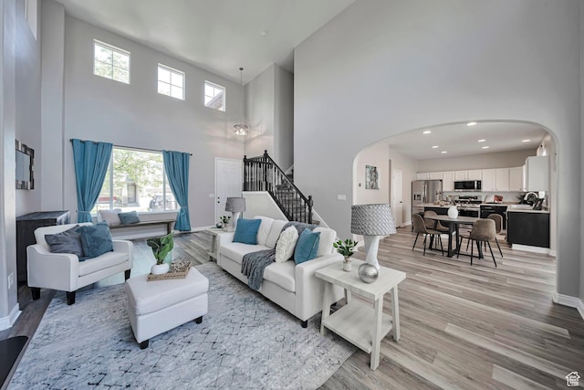 5961 W Chiswick Ct, West Jordan, UT 84081 - living room featuring arched walkways, a high ceiling, stairway, plenty of natural light, and recessed lighting