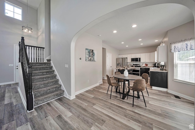 5961 W Chiswick Ct, West Jordan, UT 84081 - dining space with arched walkways, light wood finished floors, plenty of natural light, recessed lighting, and stairway