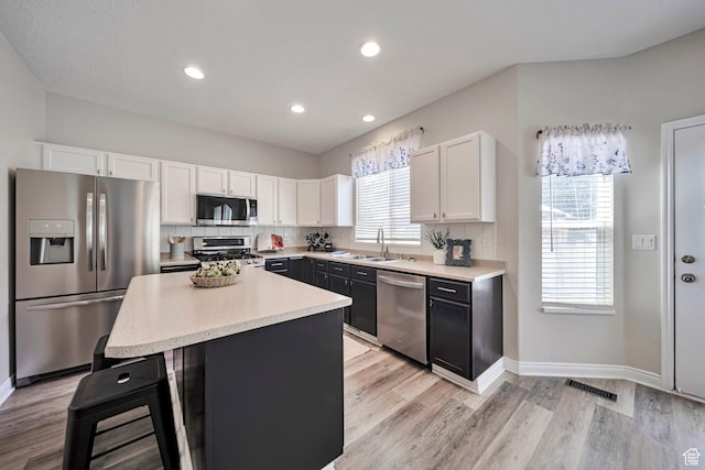 5961 W Chiswick Ct, West Jordan, UT 84081 - kitchen featuring stainless steel appliances, white cabinetry, light countertops, light wood-style flooring, and a center island