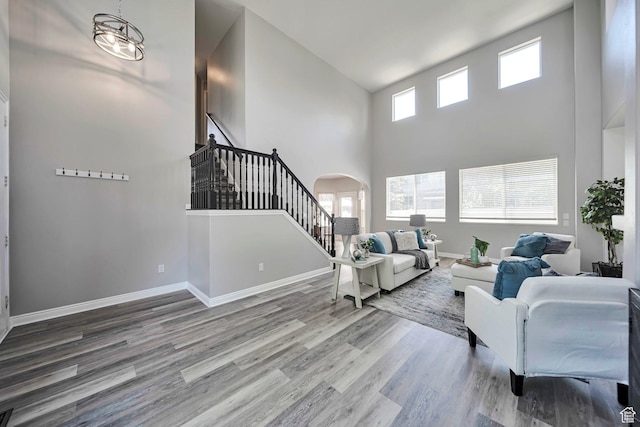 5961 W Chiswick Ct, West Jordan, UT 84081 - living room featuring stairway, a towering ceiling, arched walkways, and wood finished floors