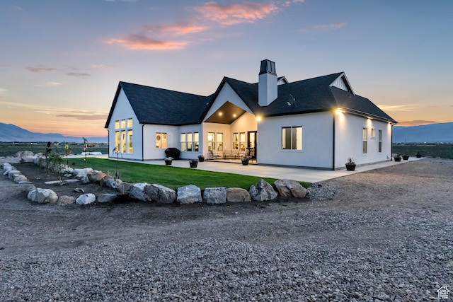 1952 N Sr 118, Monroe, UT 84754 - rear view of house with a chimney, a patio area, a lawn, a shingled roof, and stucco siding