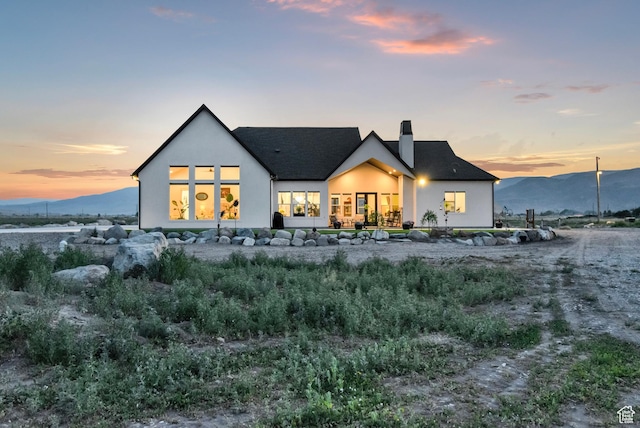 1952 N Sr 118, Monroe, UT 84754 - back of house at dusk featuring a chimney, stucco siding, a shingled roof, and a mountain view