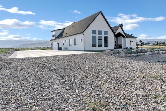 1952 N Sr 118, Monroe, UT 84754 - rear view of house featuring a mountain view, driveway, stucco siding, a garage, and roof with shingles