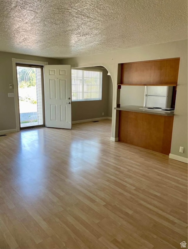 1192 W 4365 S Unit 1C, Salt Lake City, UT 84123 - unfurnished living room with a textured ceiling, plenty of natural light, wood finished floors, and arched walkways