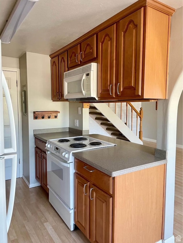 1192 W 4365 S Unit 1C, Salt Lake City, UT 84123 - kitchen featuring white appliances, light wood-style floors, arched walkways, and brown cabinetry