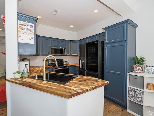 12102 S Mountain Peak Dr, Draper, UT 84020 - kitchen featuring appliances with stainless steel finishes, butcher block countertops, a peninsula, blue cabinetry, and wood finished floors