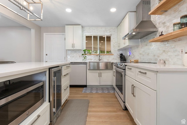 4663 S 2030 W, Taylorsville, UT 84129 - kitchen with wall chimney range hood, appliances with stainless steel finishes, wine cooler, light countertops, and white cabinetry